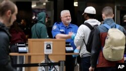 A Transportation Security Administration worker hands an ID card back to a flier, Jan. 25, 2019, at Seattle's airport. U.S. officials on Friday reached a deal to reopen the government, meaning shutdown-affected workers could head back to their jobs — and paychecks.