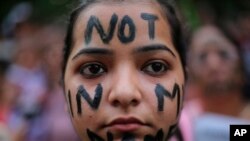 Salah seorang peserta protes mengecat wajahnya dengan "not in my name" (tidak atas namaku) dalam aksi di depan parlemen di ibu kota New Delhi, Minggu (15/4).