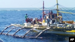 FILE - In this photo provided by Renato Etac, Chinese Coast Guard members, wearing black caps and orange life vests, approach Filipino fishermen as they confront them off Scarborough Shoal at South China Sea in northwestern Philippines, Sept. 23, 2015.