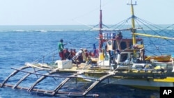 Anggota Penjaga Pantai China (memakai topi hitam dan vest oranye) mendatangi kapal nelayan Filipina di dekat Scarborough Shoal, Laut China Selatan, 23 September 2015 (Foto: dok/Renato Etac.).