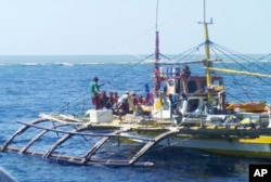 FILE - In this photo provided by Renato Etac, Chinese Coast Guard members, wearing black caps and orange life vests, approach Filipino fishermen as they confront them off Scarborough Shoal in the South China Sea, Sept. 23, 2015.