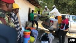 Des déplacés internes et des riverains déchargent des biens de première nécessité, de la nourriture et des couvertures à Naunde, au nord du Mozambique, le 13 juin 2018. AFP PHOTO / Joaquim Nhamirre