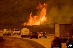 Flames from a wildfire leap above traffic on Highway 101 north of Ventura, Calif., on Wednesday, Dec. 6, 2017. (AP Photo/Noah Berger)