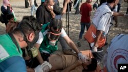 Palestinian medics evacuate a wounded youth who was shot by Israeli troops during a protest on the beach at the border with Israel near Beit Lahiya, northern Gaza Strip, Oct. 22, 2018. Another youth was fatally shot Oct. 23 during a protest along the perimeter fence with Israel, Gaza's Health Ministry said.