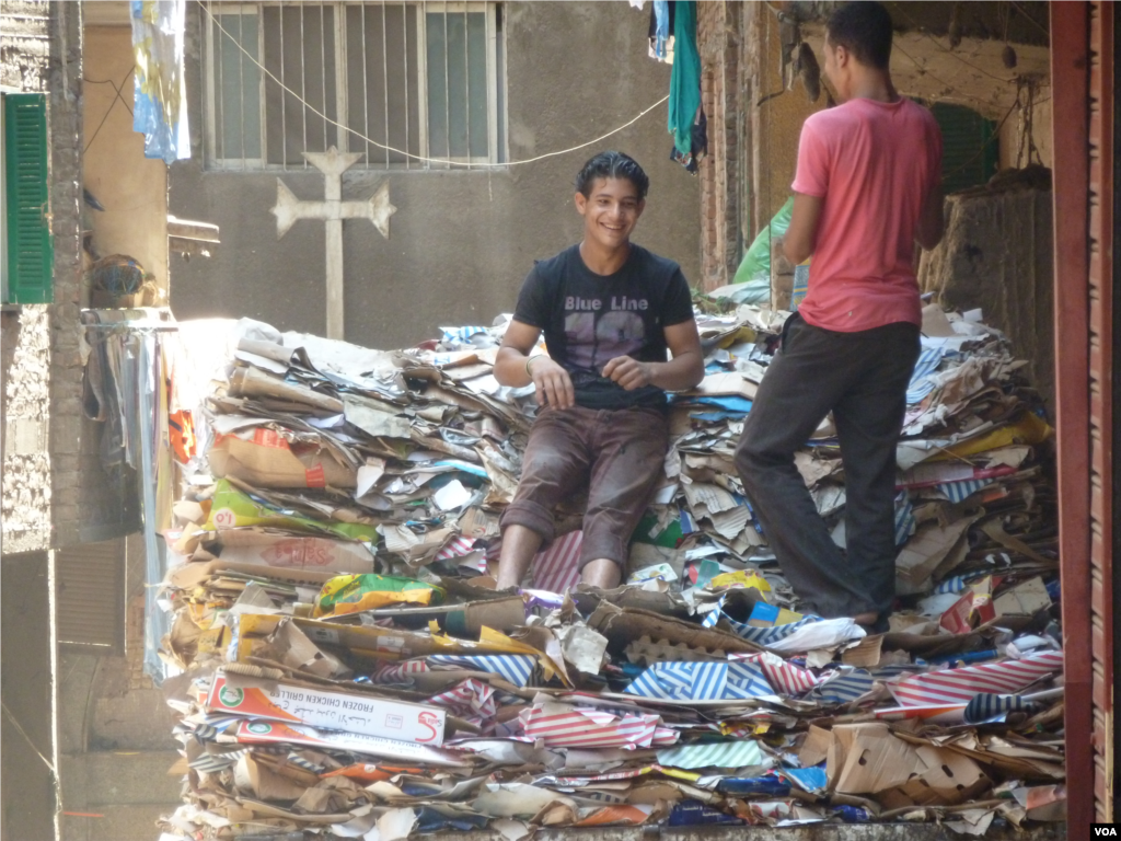 Para pemuda Kristen Koptik di antara tumpukan lipatan kardus di daerah Manshiyat Naser, atau &#39;Kota Sampah&#39; di Kairo (18/7). (VOA/S. Behn)