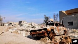 FILE - A burned out car lies amid damaged buildings in Ramadi, 70 miles (115 kilometers) west of Baghdad, Iraq, on Jan. 2, 2016.