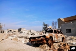 FILE - A burned out car lies amid damaged buildings in Ramadi, 70 miles (115 kilometers) west of Baghdad, Iraq, Jan. 2, 2016. Islamic militants were blamed for the attack.