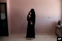 Umm Mizrah, a 25-year-old Yemeni woman, holds her son Mizrah on a scale in Al-Sadaqa Hospital in the southern Yemen city of Aden in this Feb. 13, 2018 photo.