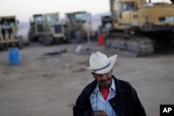 Security guard Jose Guadalupe Gonzalez walks past the remaining heavy machinery at the Ford construction site, one day after the auto company cancelled their plant's construction.