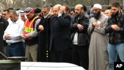 El Dr. Mohammad Yousif Abu-Salha (con las manos en la cabeza) dirige las oraciones durante el funeral de sus dos hijas en Chapel Hill.