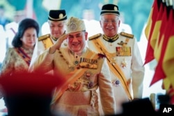 Sultan Muhammad V, center, salutes after his welcome ceremony as he walks with Malaysian Prime Minister Najib Razak, right, at the Parliament House in Kuala Lumpur, Malaysia, Dec. 13, 2016.