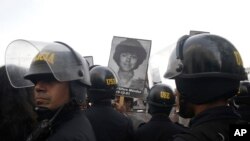 Para demonstran meneriakan slogan menentang pengampunan medis kepada mantan Presiden Alberto Fujimori. Mereka membawa foto-foto korban pembantaian selama masa dia berkuasa, pada saat bentrok dengan polisi di Lima, Peru, 25 Desember 2017.
