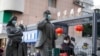 资料照片：中国武汉市，一名女子正走过带着口罩的雕塑面前。期间，世卫组织新冠溯源专家小组正在武汉考察。（2021年1月29日）