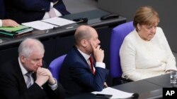 From left, German Interior Minister Horst Seehofer, German Finance Minister Olaf Scholz and German Chancellor Angela Merkel attend a budget debate at the German parliament, Bundestag. at the Reichtag building in Berlin, Germany, Tuesday, July 3, 2018.