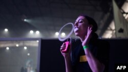 Seorang perempuan meniupkan asap rokok elektrik dalam kompetisi vaping, VapeCon, di Pretoria, Afrika Selatan, 1 September 2019. (Foto: AFP)