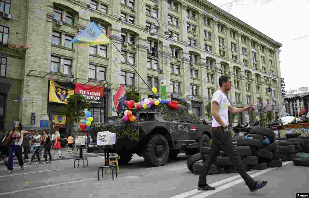 People walk next to an armoured vehicle left as a monument at the Independence Square, Kyiv, May 23, 2014.