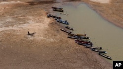 FILE - Fishing boats park downstream from Lamtakong dam during a recent period of extreme drought in Nakhon Ratchasima, Thailand. 