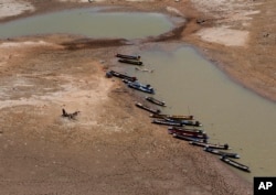 FILE - Fishing boats park downstream from Lamtakong dam during a recent period of extreme drought in Nakhon Ratchasima, Thailand, June, 29, 2015.