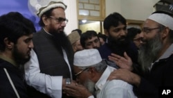 Supporters of Hafiz Saeed, second from left, head of the Pakistani religious party, Jamaat-ud-Dawa, kiss his hands as he arrived at a mosque in Lahore, Pakistan, Nov. 24, 2017. 