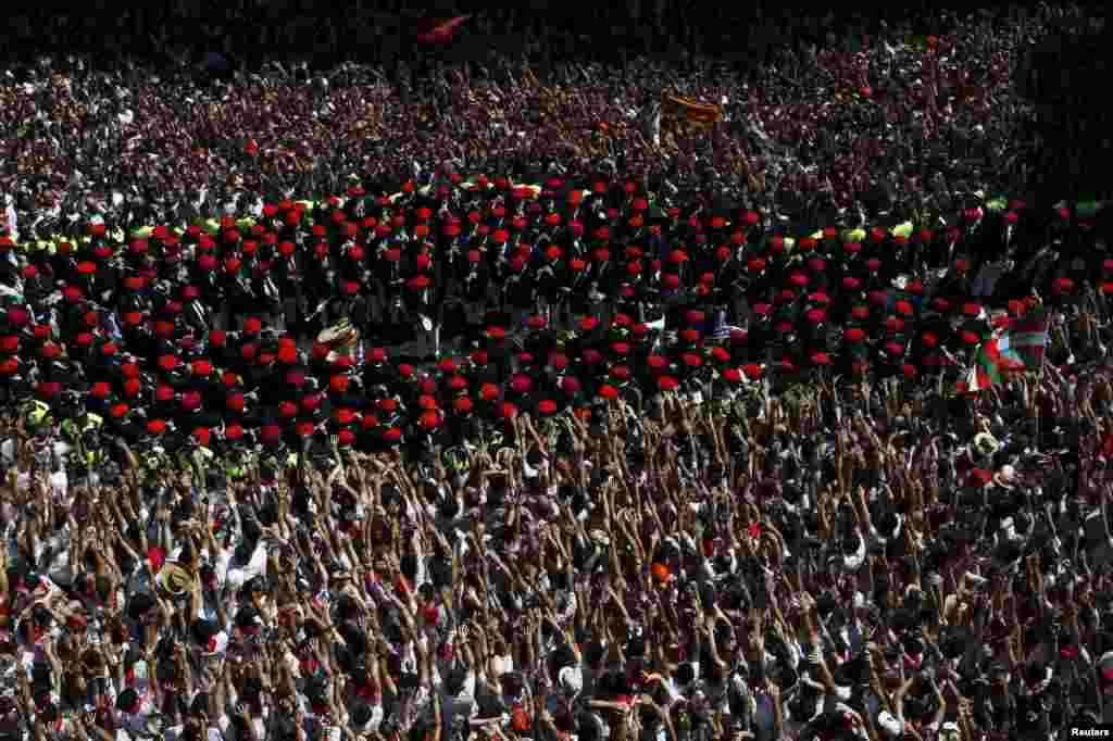 Band musik kota Pamplona melewati pengunjung di lapangan kota dalam pembukaan Festival San Fermin di Pamplona, Spanyol. Festival ini, yang dikenal dengan kerbau-kerbau yang berlarian setiap hari, dimulai dengan peluncuran roket tradisional &quot;Chupinazo&quot; dan akan berlangsung hingga 14 Juli.