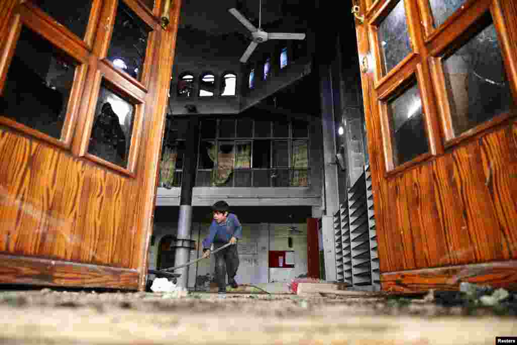 A boy cleans a damaged mosque at a site hit yesterday by an airstrike in the rebel held besieged Douma neighbourhood of Damascus.