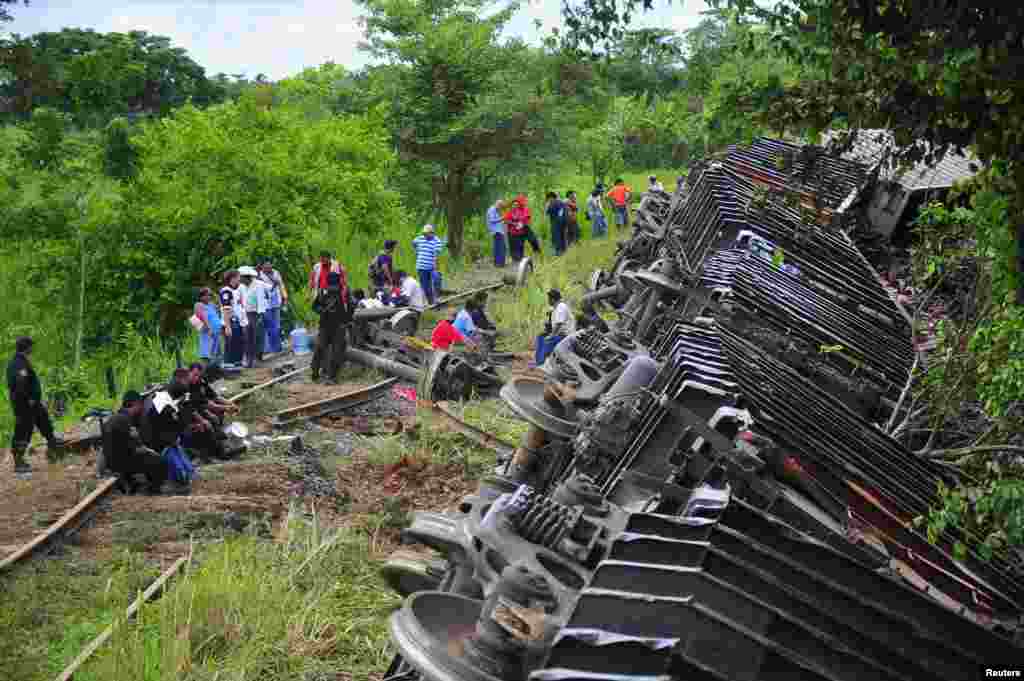 Police officers and rescue workers stand next to the overturned carriages of a derailed train in Huimanguillo, in the Mexican state of Tabasco, Aug. 25, 2013.