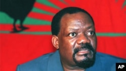 Jonas Savimbi, fotografado em data não determinada, em frente a uma bandeira da UNITA, com o lendário galo negro. Savimbi foi morto há 9 anos pelas forças governamentais, na província do Moxico.