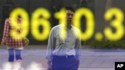A man is reflected on an electric board showing the Nikkei 225 index in Tokyo, Japan, August 3, 2011