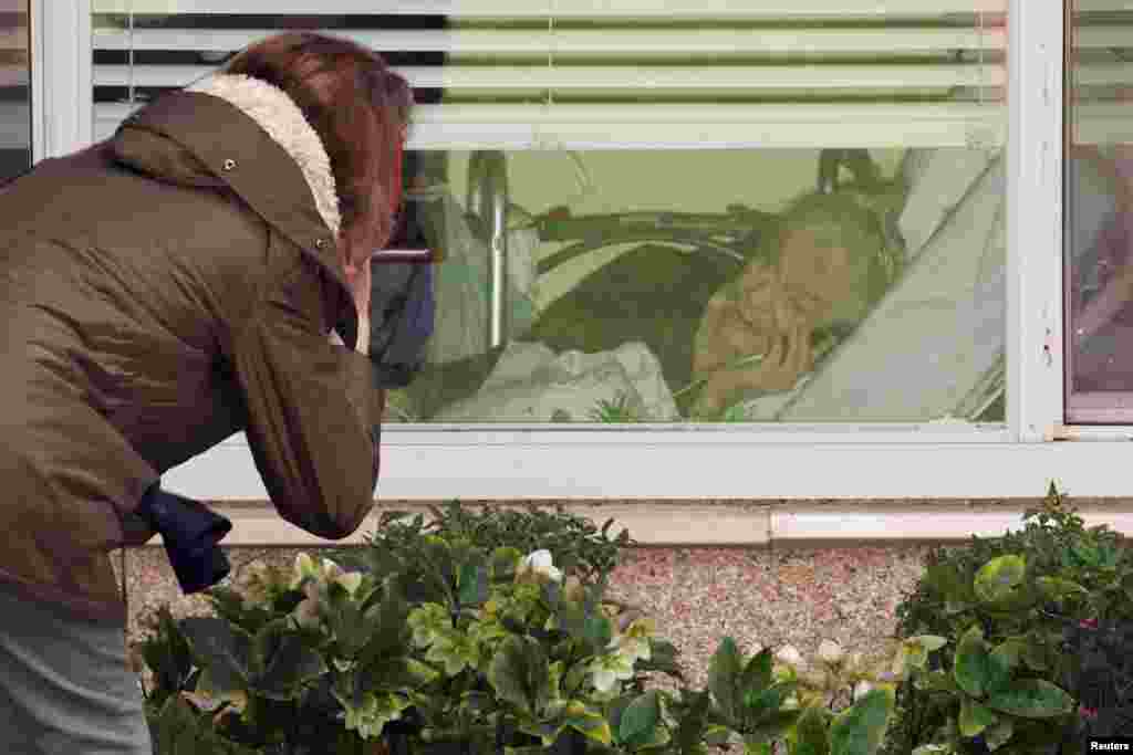 Lori Spencer talks on the phone through a window with her mother, Judie Shape, who is 81 and was tested for coronavirus, at the Life Care Center of Kirkland, the long-term care facility linked to several confirmed coronavirus cases in the state, in Kirkland, Washington, March 8, 2020