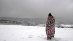A migrant walks through the snow wrapped in a blanket at the Lipa camp northwestern Bosnia, near the border with Croatia, Saturday, Dec. 26, 2020.