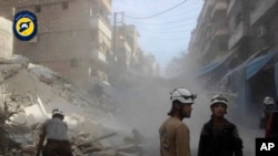 FILE - In this picture provided by the Syrian Civil Defense group known as the White Helmets, Syrian Civil Defense workers search through the rubble in rebel-held eastern Aleppo, Syria, Oct. 12, 2016. 