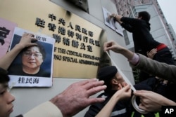 FILE - Protesters post photos of missing booksellers during a protest outside the Liaison of the Central People's Government in Hong Kong, Jan. 3, 2016.