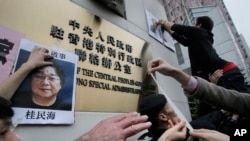 Protesters post photos of missing booksellers during a protest outside the Liaison of the Central People's Government in Hong Kong, Jan. 3, 2016. 