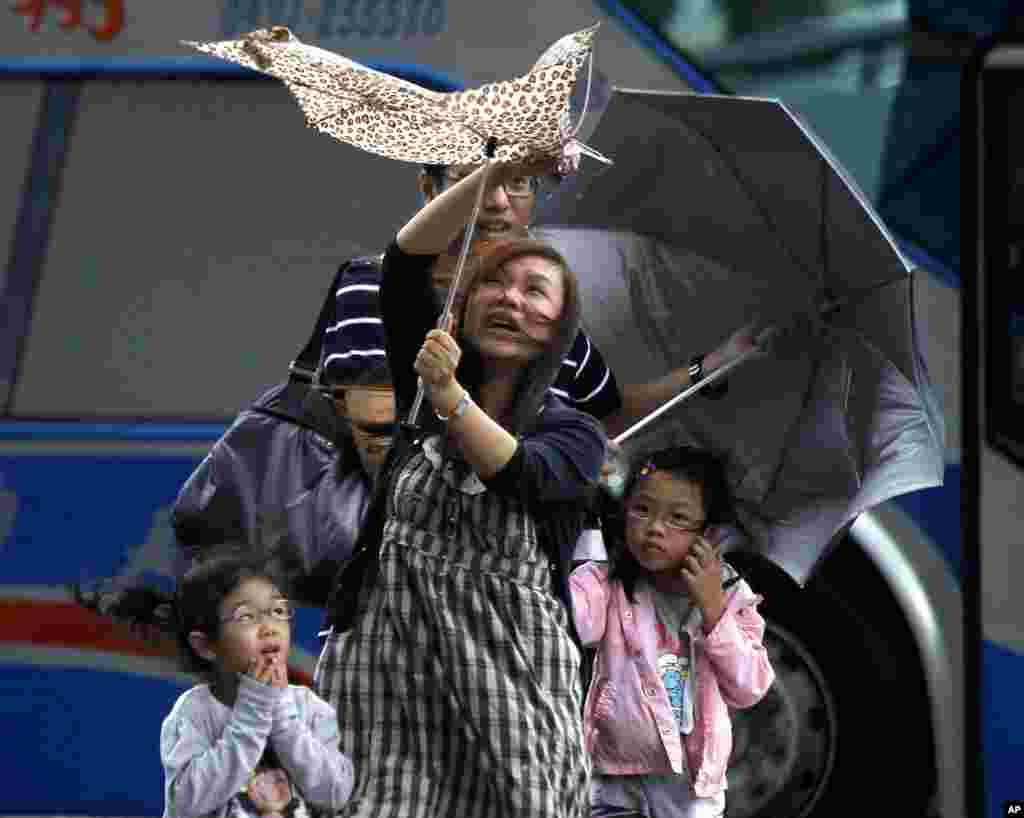 A mother and her family brave winds from Typhoon Saola in Taipei, Taiwan, August 1, 2012.