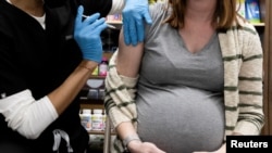 FILE - A pregnant woman receives a COVID vaccine at a pharmacy in Schwenksville, Pennsylvania, Feb. 11, 2021.