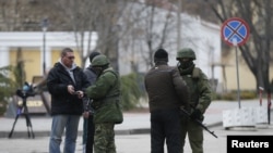 Armed men check journalists documents around the regional parliament building in the Crimean city of Simferopol March 1, 2014.