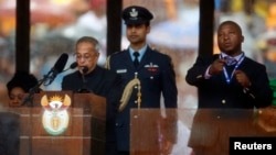 India's President Pranab Mukherjee speaks at the podium as the fake sign language interpreter (R) punches the air beside him during a memorial service for late South African President Nelson Mandela at the FNB soccer stadium in Johannesburg, Dec. 10, 201