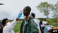 Un membre du personnel médical mesure la température d'un homme à titre préventif contre le coronavirus COVID-19, à la frontière entre la RDC et le Burundi, le 18 mars 2020. (Photo by ONESPHORE NIBIGIRA / AFP)