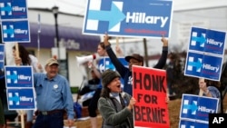 FILE - A Sen. Bernie Sanders supporter cheers for passing motorists to honk, amongst a group of Hillary Clinton backers outside the University of South Carolina School of Law in this Feb. 23, 2016 photo.