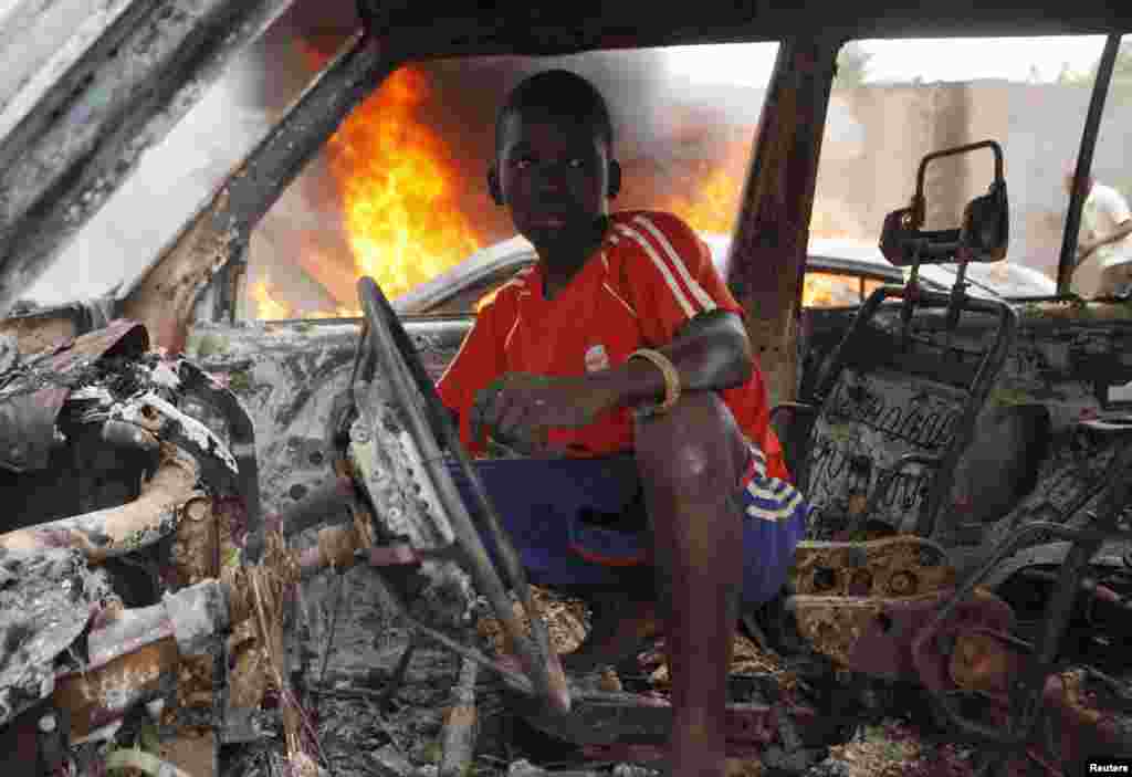 Seorang anak laki-laki berada di dalam rongsokan sebuah mobil yang hangus terbakar di Bangui, Republik Afrika Tengah.