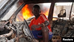 A Christian youth squats inside a burnt-out car in Bangui, Dec. 10, 2013. 