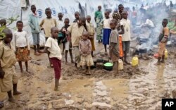 FILE - Refugee children stand in the mud near tents holding hundreds of other refugees who have fled from Burundi, at the Gashora refugee camp, in the Bugesera district of Rwanda, April 21, 2015.