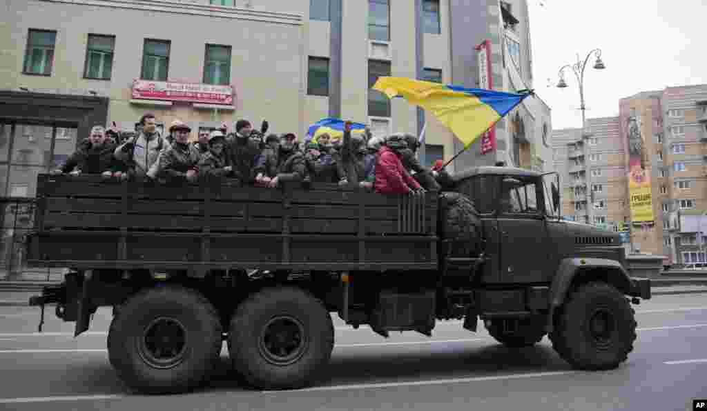 Protesters ride atop of what appears to be a military truck, in central Kyiv. 