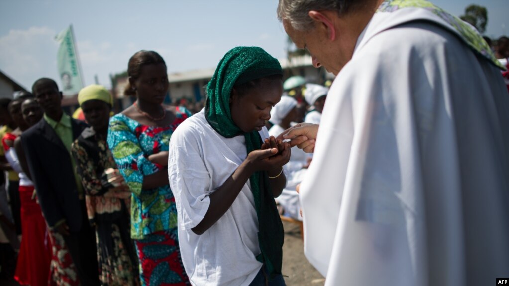 Un prêtre distribue l’eucharistie au cours d’une messe dans un camp des personnes déplacées à la périphérie de Goma, Nord-Kivu, 25 novembre 2012.