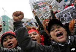 Domestic helpers and their supporters shout slogans while holding pictures of 23-year-old Indonesian maid Erwiana Sulistyaningsih during a protest in Hong Kong, Jan. 19, 2014. The Indonesian maid was allegedly brutally tortured by her employers for months; she was eventually sent back to Indonesia.