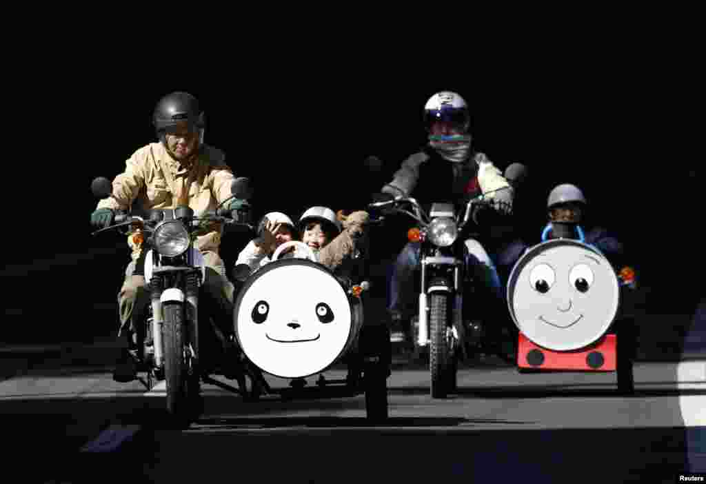 Sadao Kimbara (L) and his daughter-in-law Sayuri (2nd R) ride on Honda motorcycles with sidecars he made out of oil barrels, as his grandchildren Rio (2nd L), Ruka (C), pet dog Tida and Rui sit in the sidecars in Ome, outskirts of Tokyo, Japan.