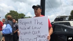 A man holds a sign supporting President Donald Trump while joining a group of pro-Trump demonstrators outside Suffolk Community College in Brentwood, New York, July 28, 2017.