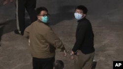 Hong Kong activists Joshua Wong, right, and Ivan Lam, left, are escorted by Correctional Services officers to prison, in Hong Kong, Wednesday, Dec. 2, 2020. (AP Photo/Kin Cheung)