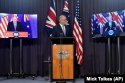 Australia's Prime Minister Scott Morrison, center, appears on stage with video links to Britain's Prime Minister Boris Johnson, left, and U.S. President Joe Biden at a joint press conference at Parliament House in Canberra, Thursday, Sept. 16, 2021.