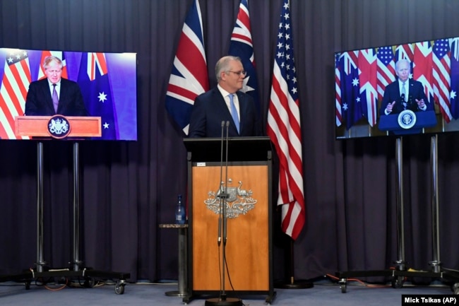 Australia's Prime Minister Scott Morrison, center, appears on stage with video links to Britain's Prime Minister Boris Johnson, left, and U.S. President Joe Biden at a joint press conference at Parliament House in Canberra, Thursday, Sept. 16, 2021.